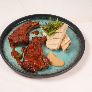 Grilled lamb rack served with rich Singapore-style Tulang Merah sauce, smooth garlic purée, fluffy Syrian hummus and sourdough bread to soak up all the flavours